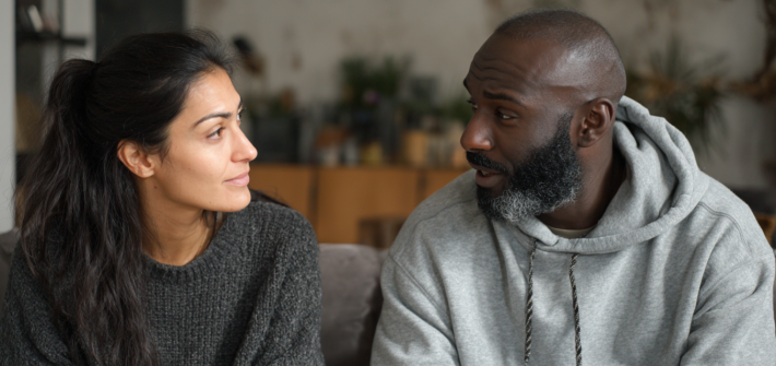 A couple sitting on a couch having a serious conflict resolution conversation