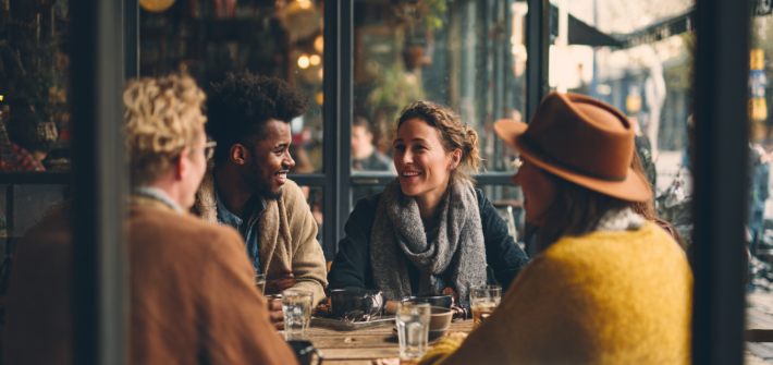 A group of four friends happily chatting at a cafe