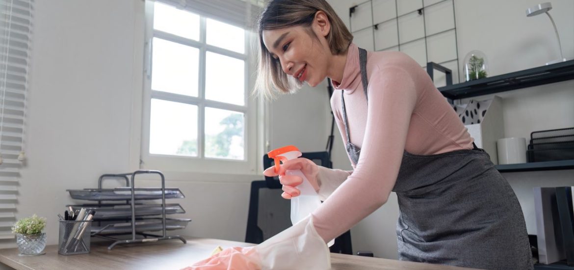 A woman in an office cleaning and organizing a desk
