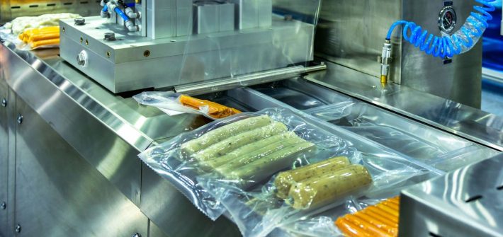 A conveyer belt packaging ultra-processed foods, such as sausages