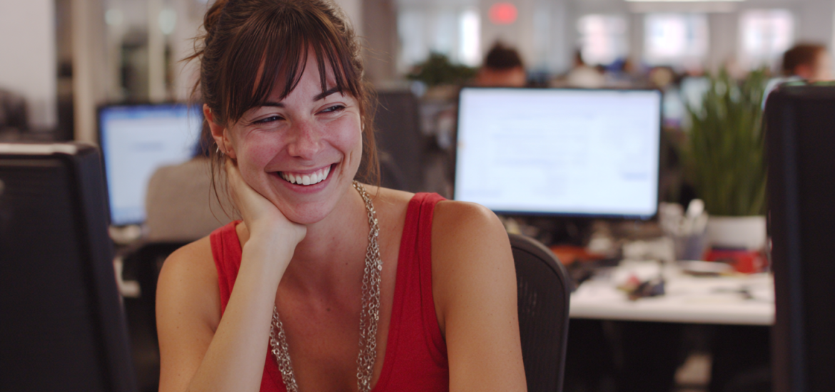 A happy woman who is doing meaningful work at her desk job