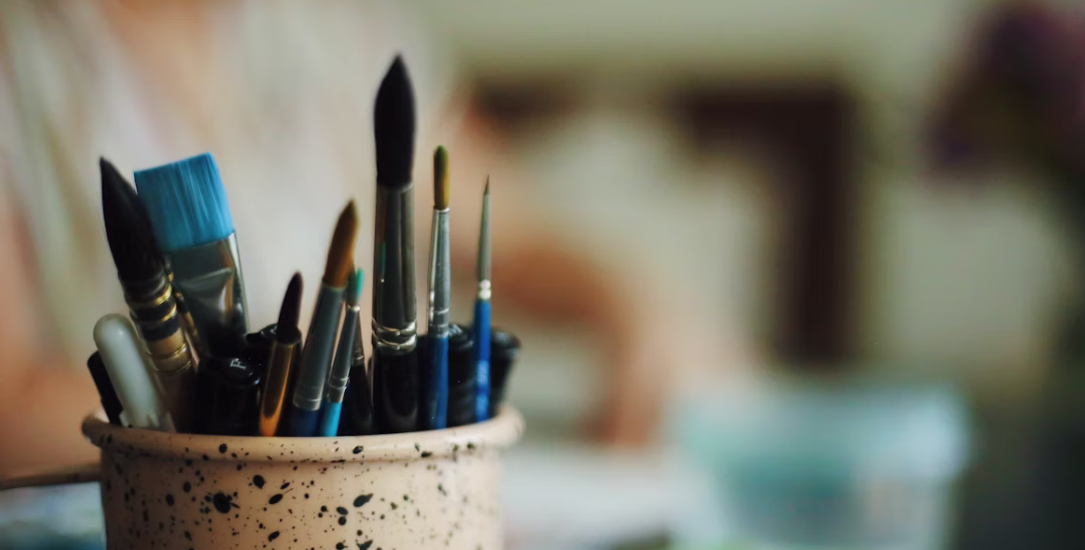 A cup of paint brushes in a table