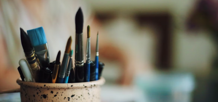 A cup of paint brushes in a table