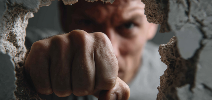 A man punching through a wall to overcome limiting beliefs