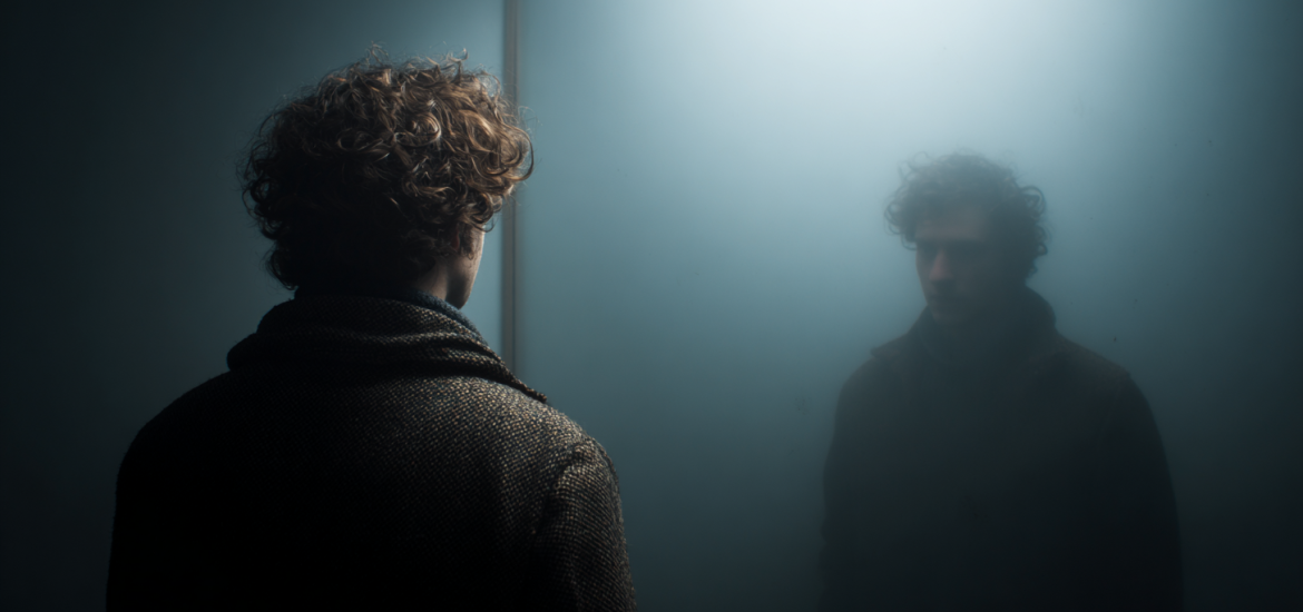 A man looking back at a reflection of himself as an example of mind-body dualism