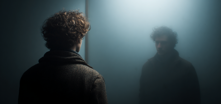 A man looking back at a reflection of himself as an example of mind-body dualism