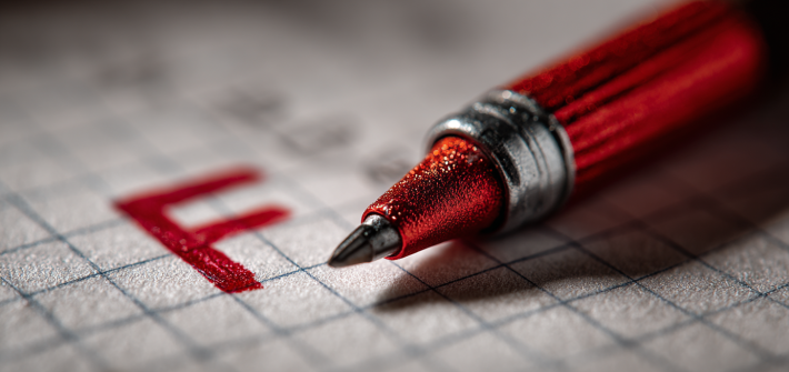 A red F on a piece of paper next to a red pen, representing learning from failure