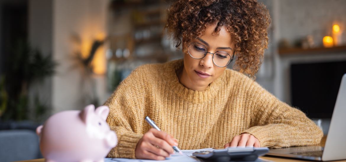 A woman working with a calculator and laptop to use the zero-based budget