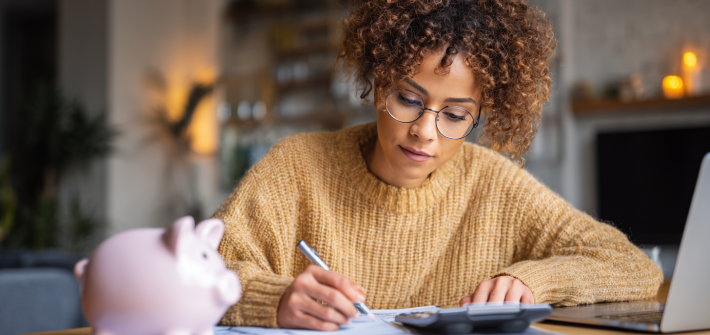 A woman working with a calculator and laptop to use the zero-based budget