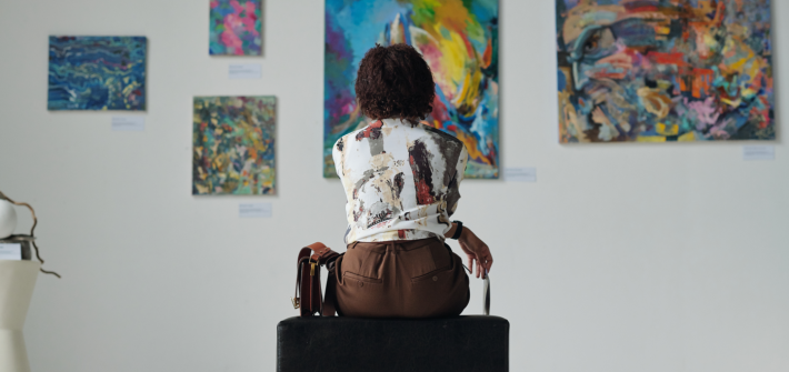 A woman in a museum sitting on a chair and looking at paintings