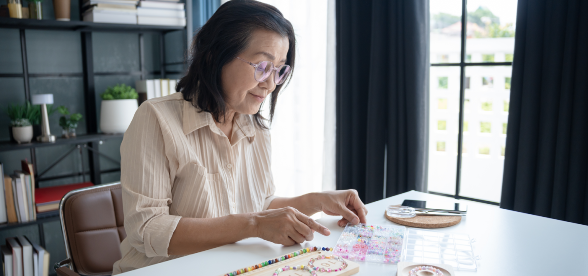 A woman creating bracelet bead art on a table