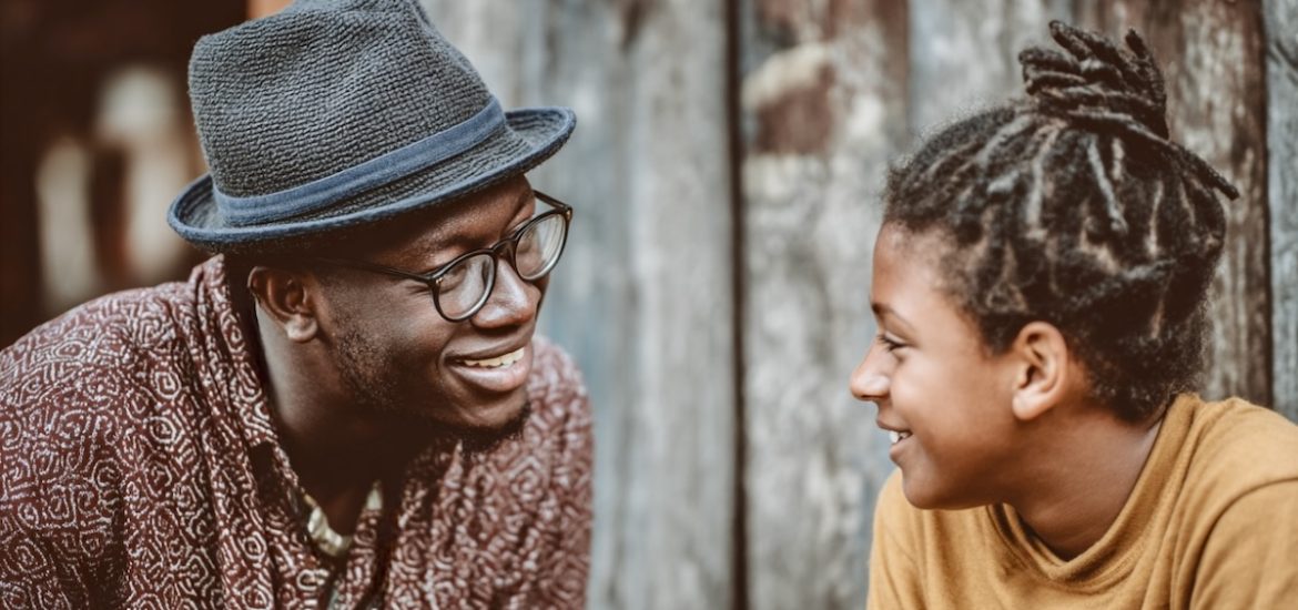 A man in a hat (a mentor) and a young person looking at each other and smiling