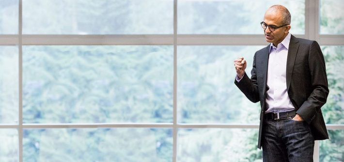 Microsoft CEO Satya Nadella standing in front of a large window while talking passionately illustrates empathetic leadership