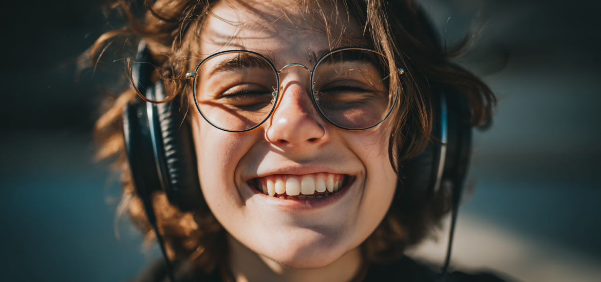 A woman smiling while listening to a free audiobook app through her headphones