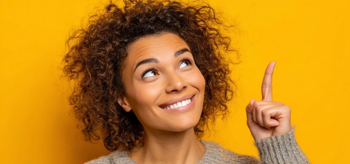 A smiling woman with curly hair looking and pointing upward illustrates how to stop feeling sorry for yourself